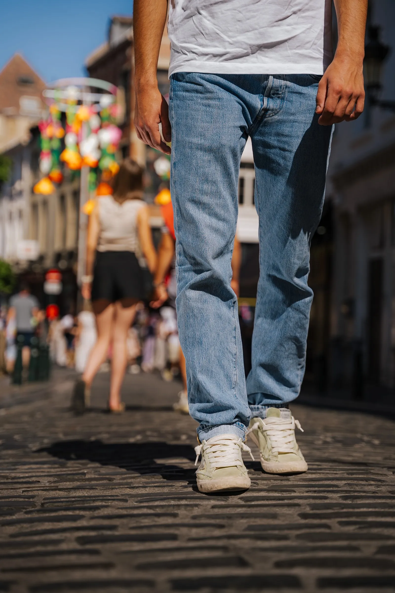 Pedestrian on the cobbles of a shopping street, framed at the legs