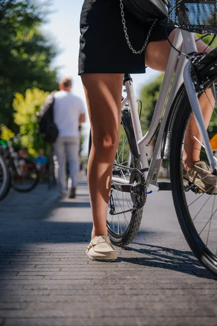 Cycliste à l'arrêt dans une rue piétonne, cadrée aux jambes