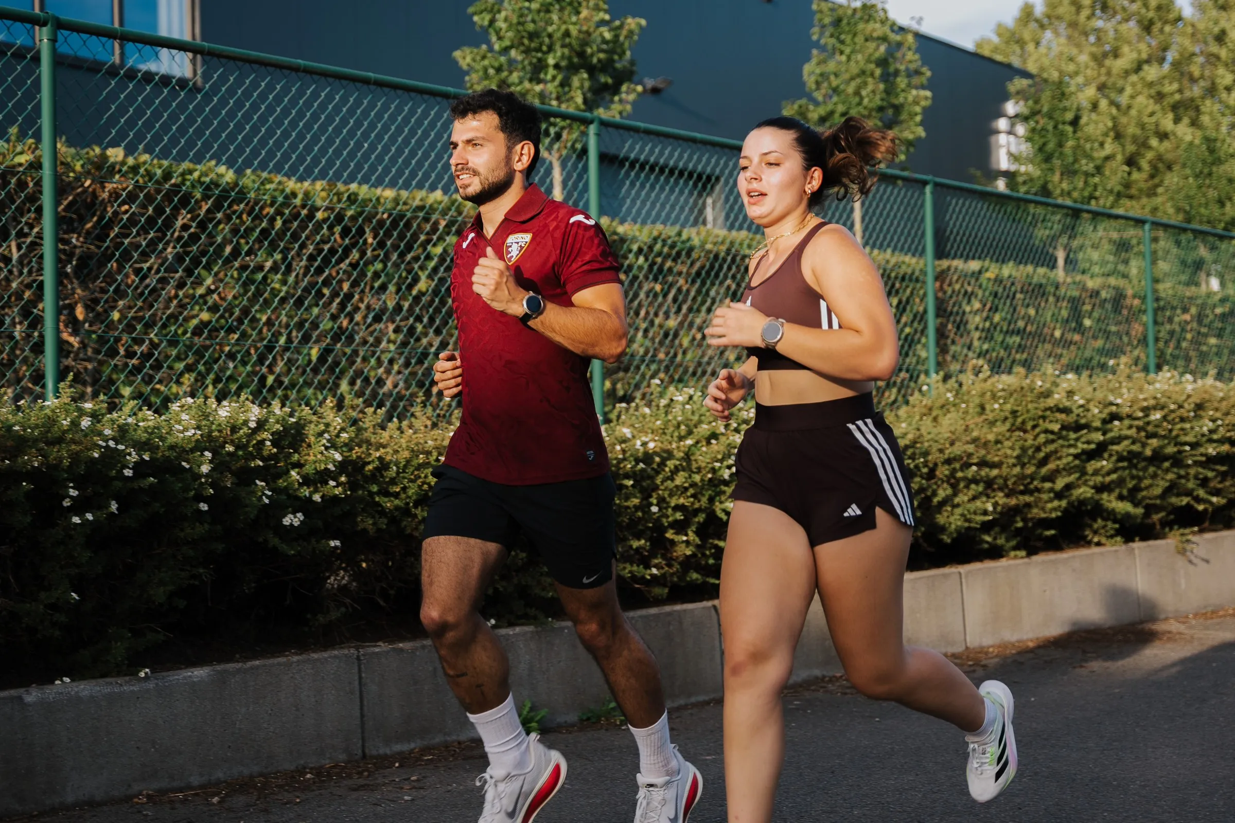 Two runners training alongside a hedge