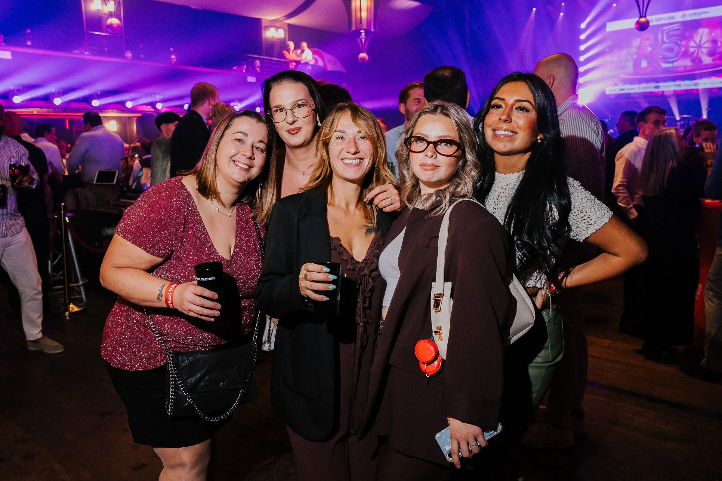 Group of guests posing in a room lit in purple