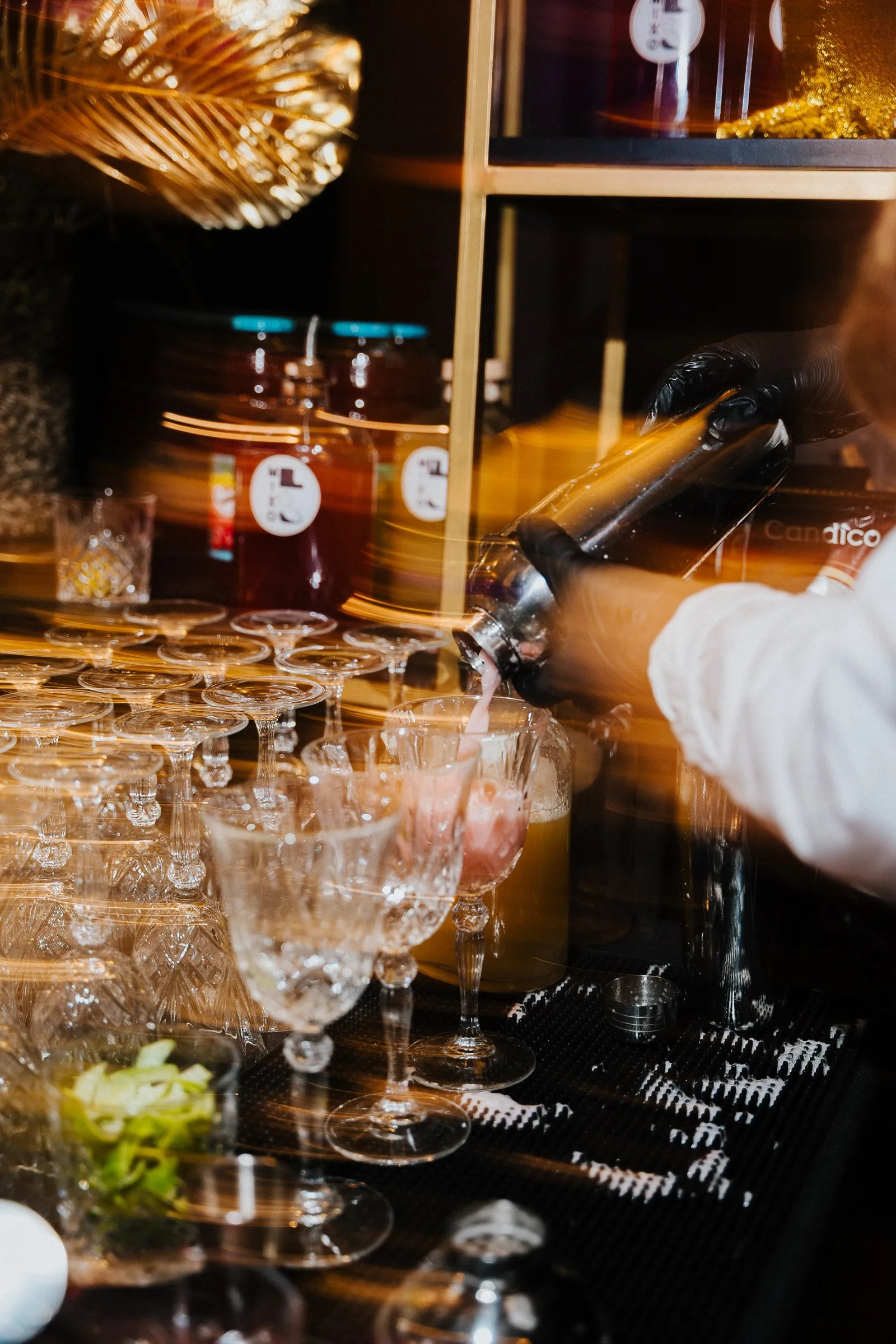 Drinks being poured over rows of glasses
